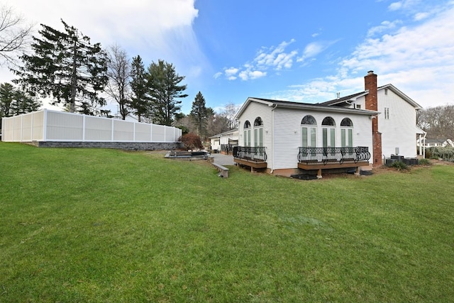 back of property with a deck and a lawn