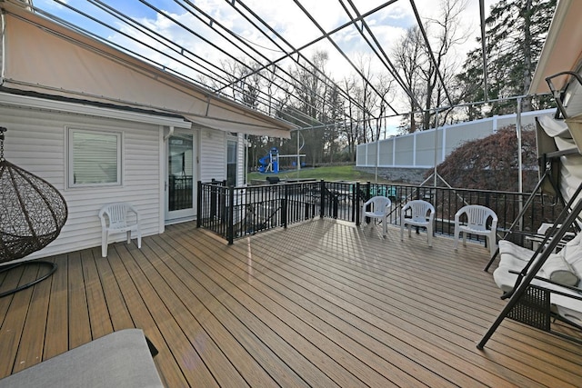 wooden deck featuring a playground and a trampoline