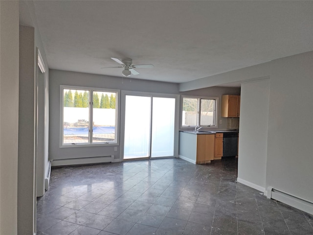 unfurnished living room with ceiling fan, a healthy amount of sunlight, sink, and a baseboard radiator