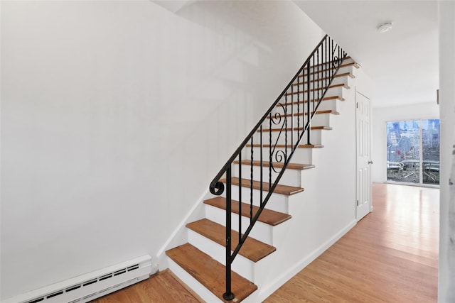 staircase with wood-type flooring and baseboard heating