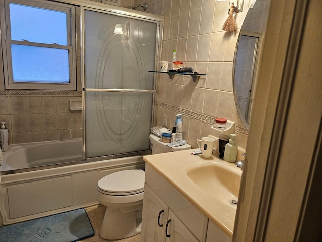 full bathroom featuring vanity, toilet, bath / shower combo with glass door, and tile walls