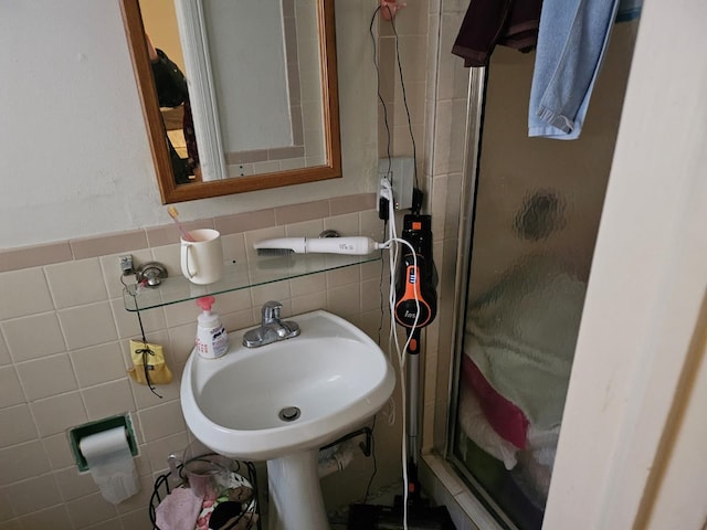 bathroom with sink, tile walls, and walk in shower