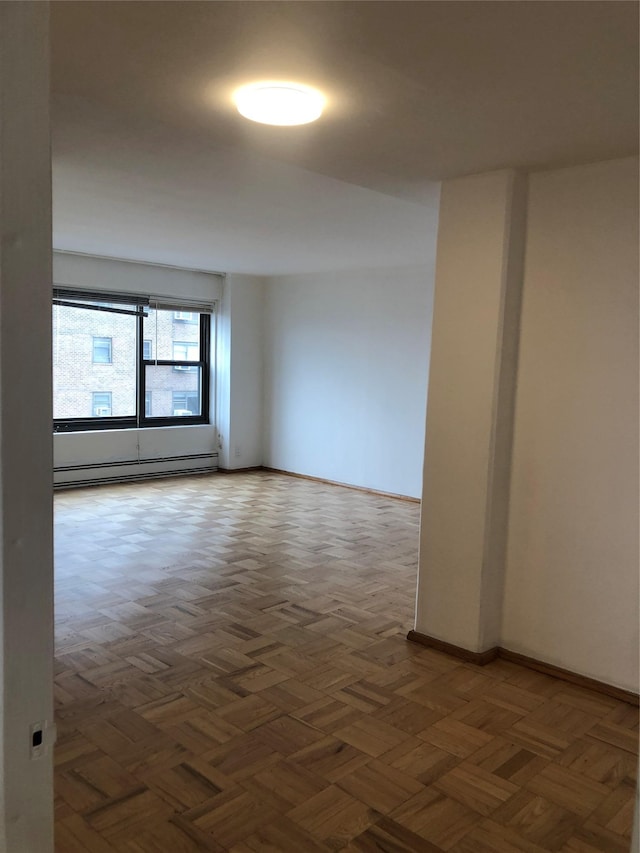 spare room featuring a baseboard heating unit and baseboards