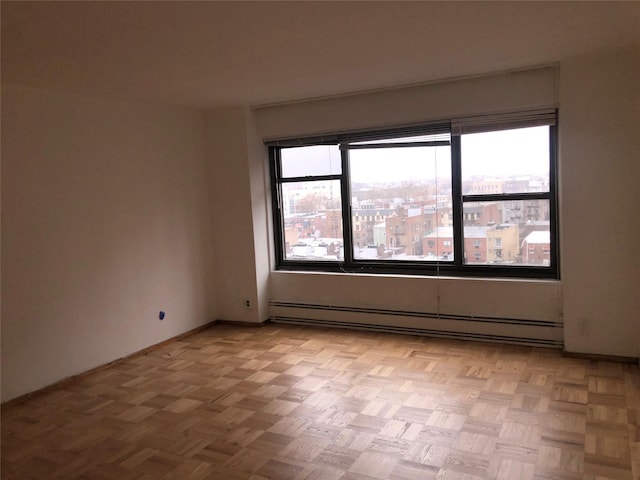 unfurnished room with baseboard heating and light parquet flooring