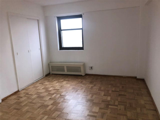 unfurnished bedroom with radiator heating unit and a closet