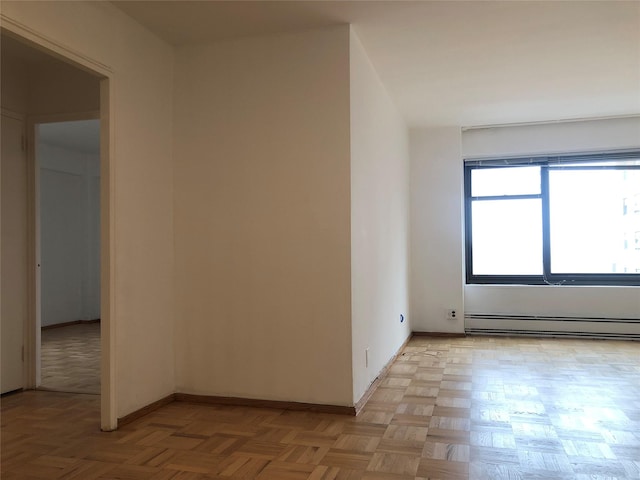 empty room with light parquet flooring and a baseboard radiator