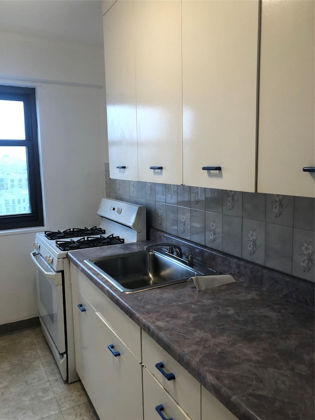 kitchen featuring white cabinetry, dark countertops, white range with gas stovetop, and tasteful backsplash