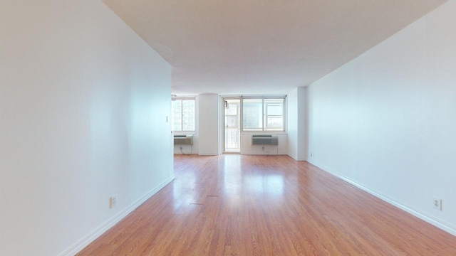 unfurnished living room with a wall mounted air conditioner and light hardwood / wood-style floors