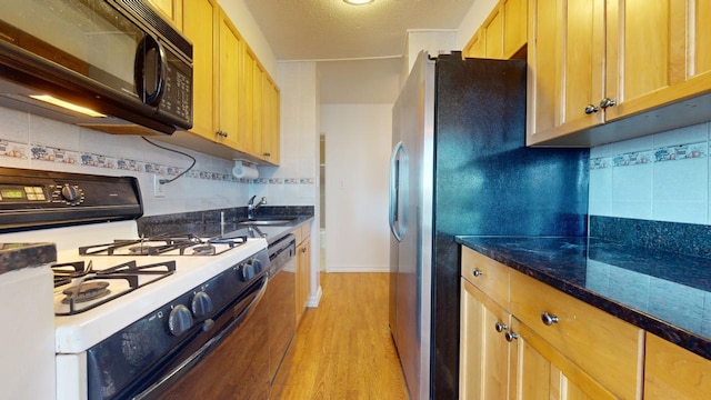 kitchen featuring a textured ceiling, dishwasher, tasteful backsplash, white range with gas stovetop, and light hardwood / wood-style flooring