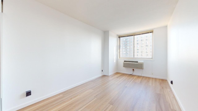 spare room with a wall unit AC and light wood-type flooring