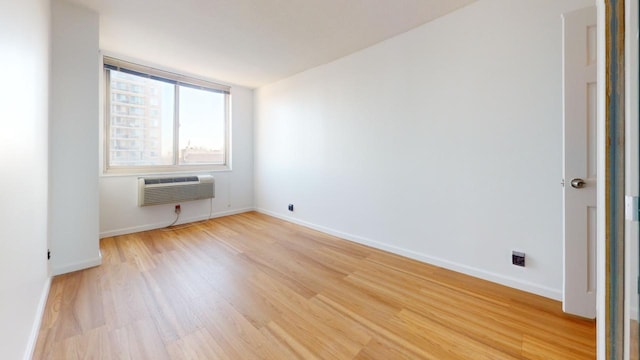 empty room with light wood-type flooring and a wall mounted air conditioner