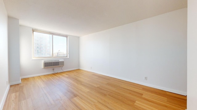 empty room featuring light wood-type flooring and a wall mounted air conditioner