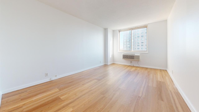 unfurnished room featuring an AC wall unit and light hardwood / wood-style flooring