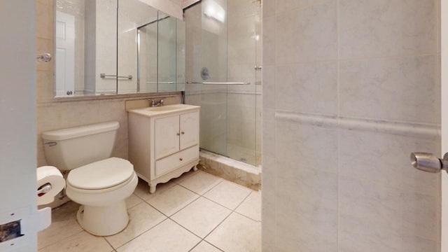 bathroom with toilet, vanity, tile patterned flooring, tile walls, and a shower with shower door