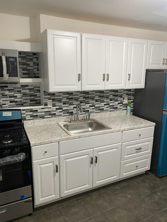 kitchen featuring backsplash, white cabinetry, sink, and appliances with stainless steel finishes