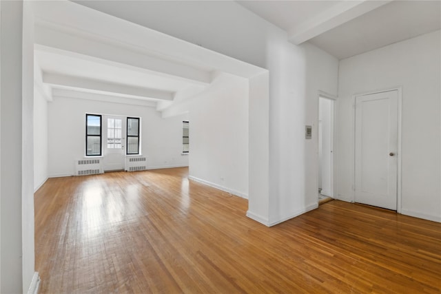 spare room with beamed ceiling, radiator heating unit, and hardwood / wood-style flooring