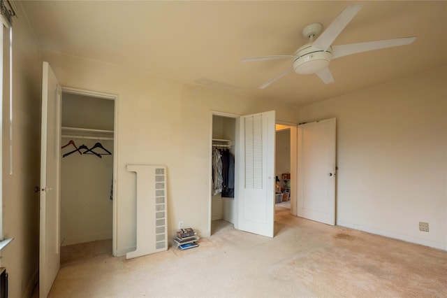 unfurnished bedroom with light carpet, two closets, and ceiling fan