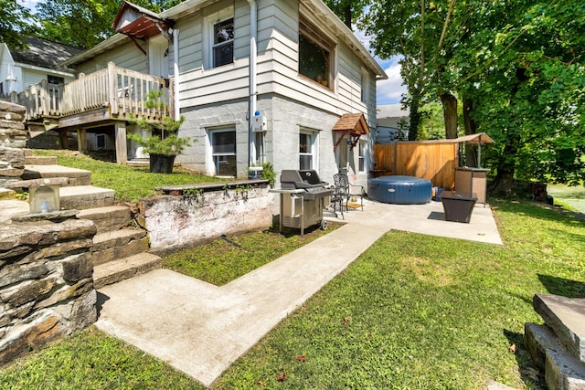 rear view of property featuring a deck, a patio, and a yard