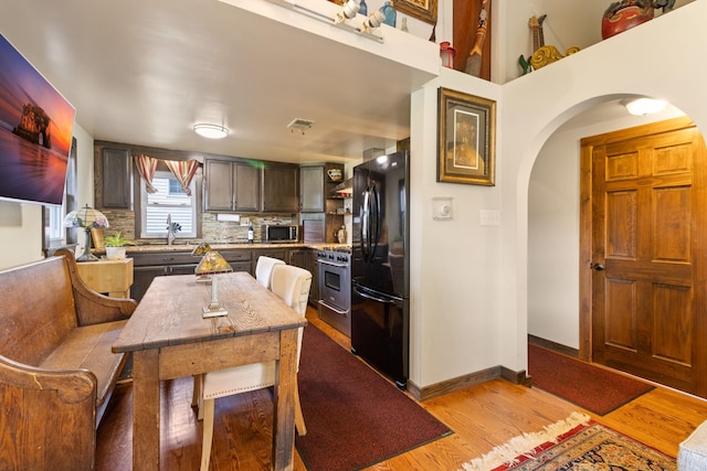 kitchen featuring light hardwood / wood-style floors, dark brown cabinetry, appliances with stainless steel finishes, and tasteful backsplash