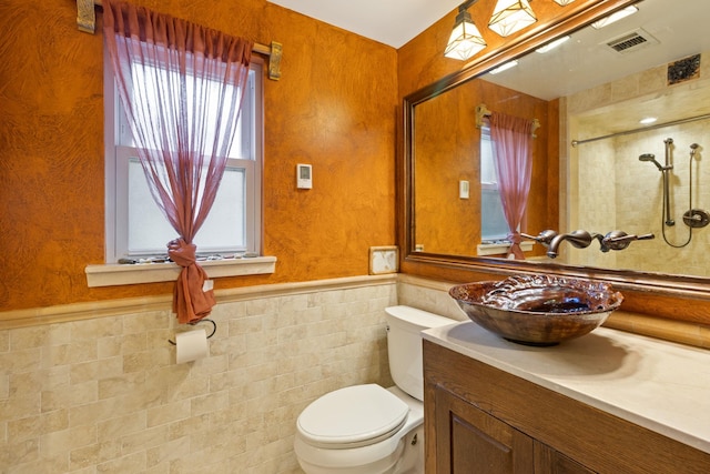 bathroom featuring vanity, toilet, tile walls, and plenty of natural light