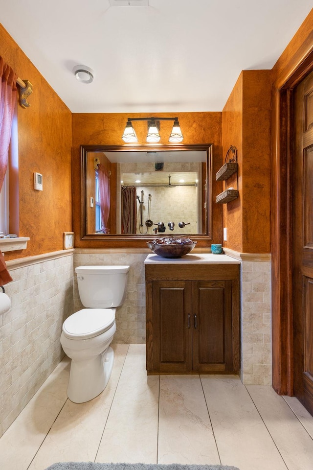 bathroom with tile patterned floors, vanity, toilet, and tile walls