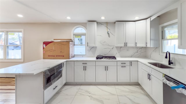 kitchen featuring white cabinetry, sink, kitchen peninsula, decorative backsplash, and appliances with stainless steel finishes