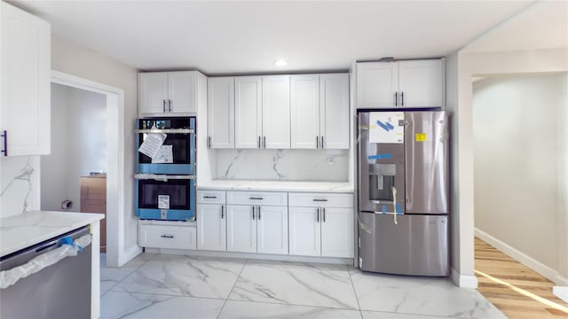 kitchen with backsplash, white cabinetry, light stone countertops, and stainless steel appliances