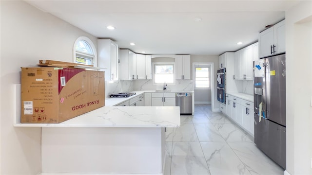 kitchen featuring backsplash, white cabinetry, sink, and stainless steel appliances