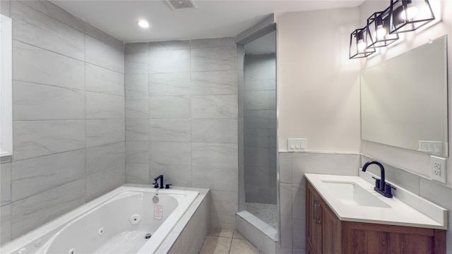 bathroom with tile patterned floors, vanity, independent shower and bath, and tile walls