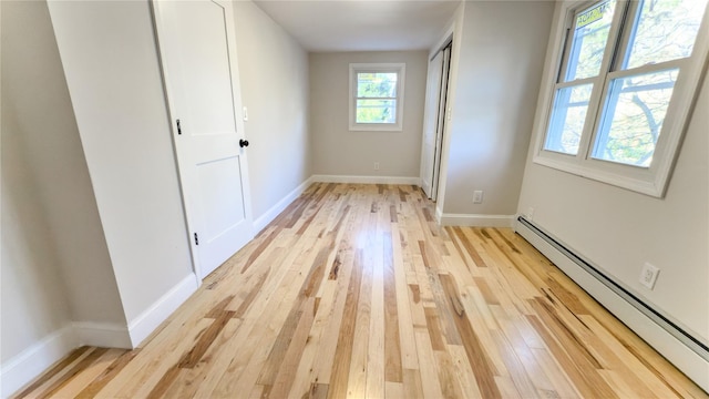 unfurnished bedroom featuring light wood-type flooring and a baseboard heating unit