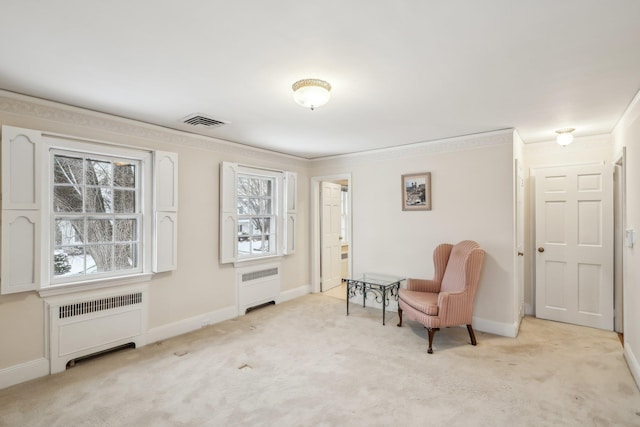 sitting room featuring light colored carpet, radiator heating unit, and crown molding