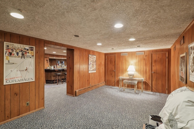 misc room featuring a baseboard radiator, carpet, and wood walls