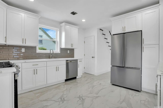 kitchen with white cabinets, backsplash, sink, and appliances with stainless steel finishes