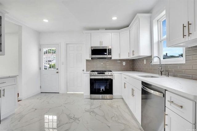 kitchen featuring light stone countertops, sink, stainless steel appliances, backsplash, and white cabinets