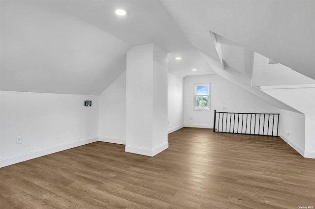 additional living space featuring vaulted ceiling and hardwood / wood-style flooring