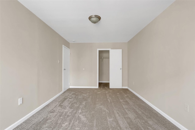 unfurnished bedroom featuring a walk in closet, light carpet, and a closet