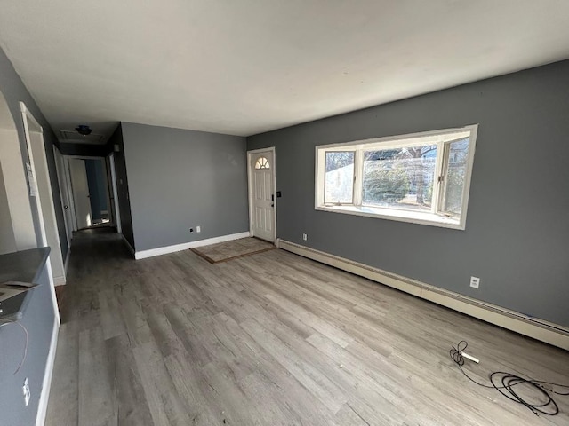 unfurnished living room featuring hardwood / wood-style floors and a baseboard radiator