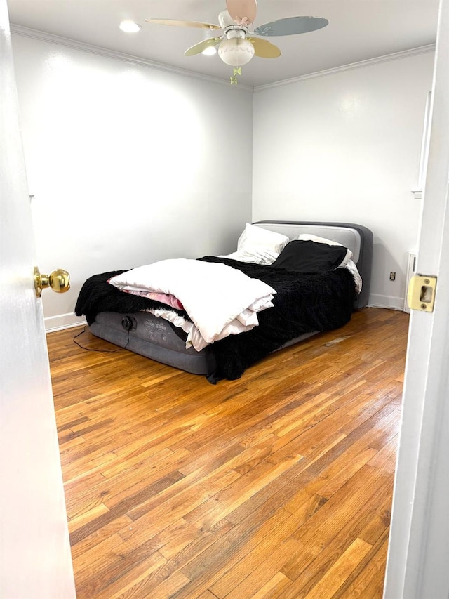 bedroom with ornamental molding, ceiling fan, and light hardwood / wood-style flooring