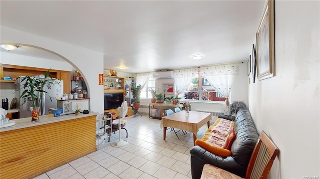 living room featuring light tile patterned floors, radiator heating unit, and a wall unit AC