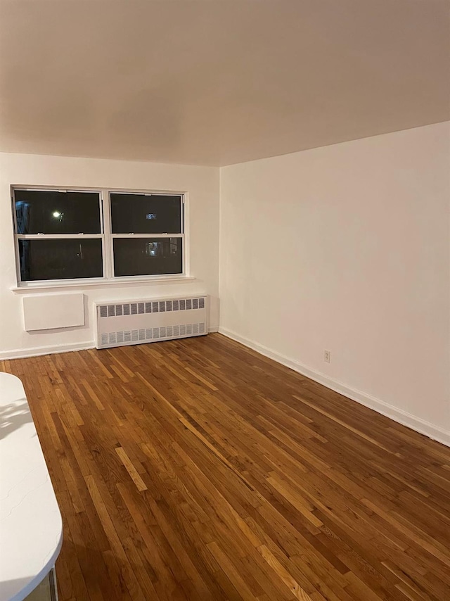 unfurnished living room featuring radiator heating unit and dark hardwood / wood-style floors