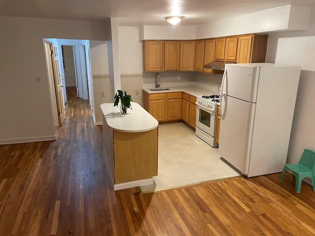 kitchen with kitchen peninsula, sink, white appliances, and light hardwood / wood-style flooring