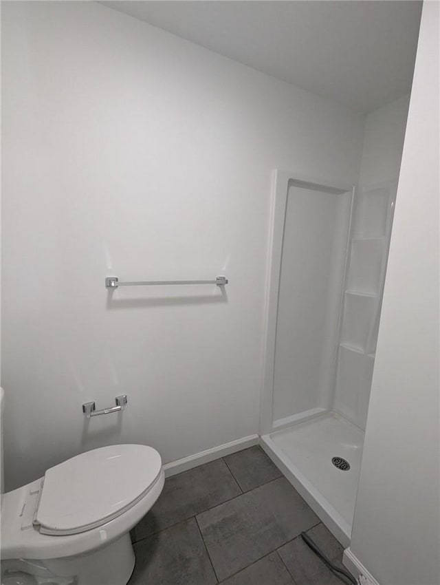 bathroom featuring tile patterned flooring, toilet, and a shower