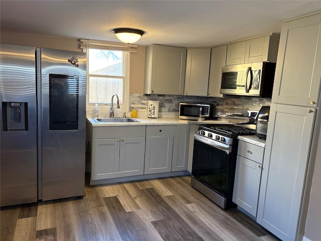 kitchen featuring backsplash, dark wood-type flooring, sink, gray cabinets, and appliances with stainless steel finishes