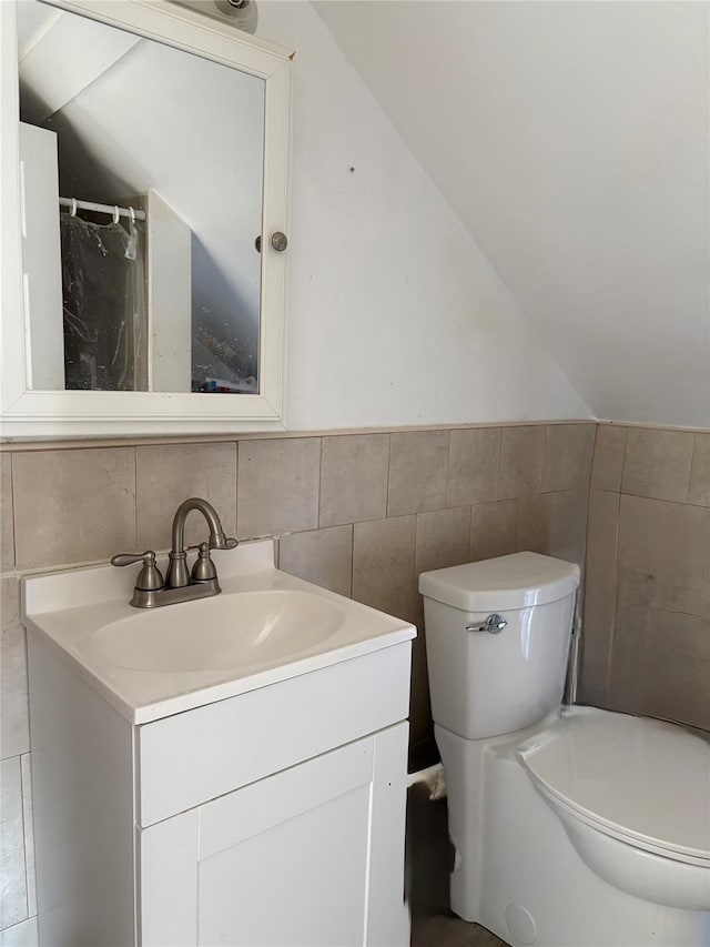 bathroom featuring vanity, tile walls, and vaulted ceiling