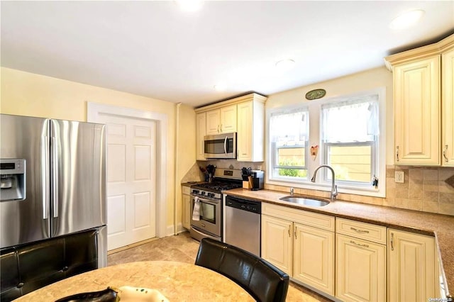 kitchen with tasteful backsplash, sink, appliances with stainless steel finishes, and cream cabinets