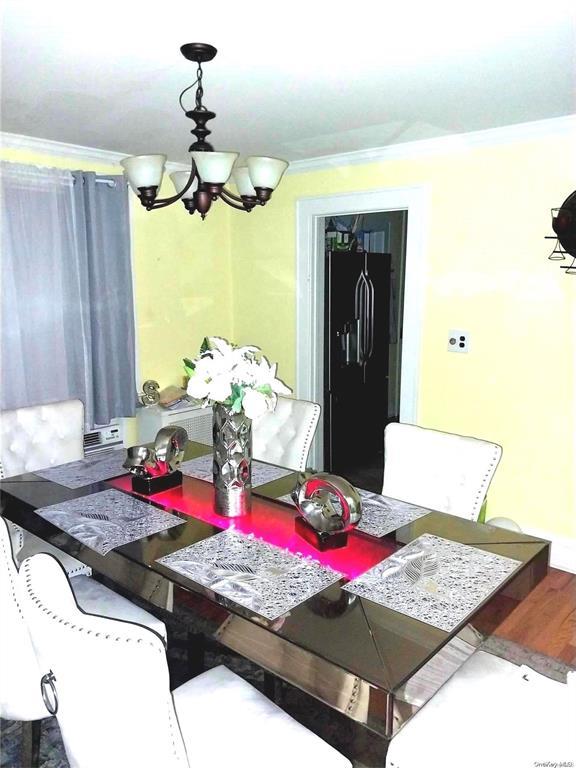 dining space featuring hardwood / wood-style floors, ornamental molding, and an inviting chandelier