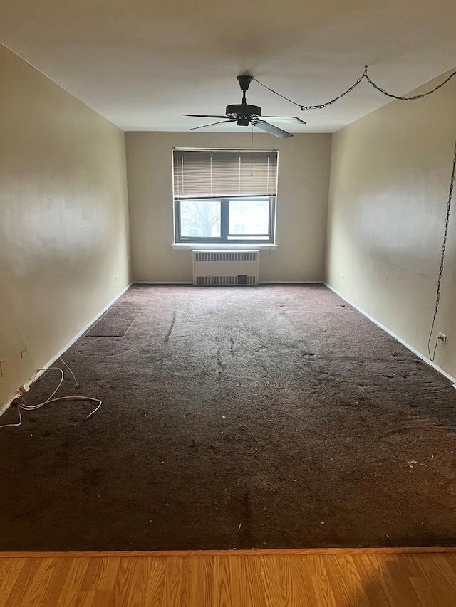 unfurnished room with carpet, radiator, and ceiling fan