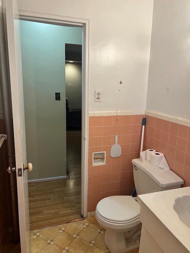 bathroom featuring tile patterned flooring, vanity, toilet, and tile walls