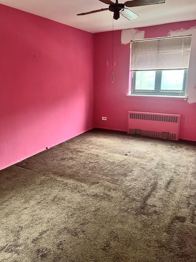 carpeted spare room featuring ceiling fan and radiator heating unit