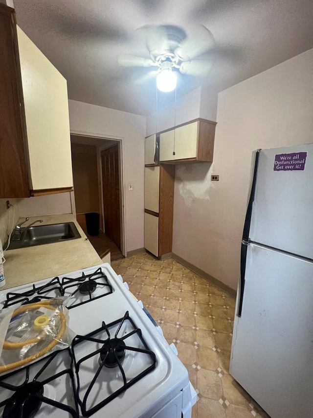 kitchen featuring ceiling fan, sink, and white appliances